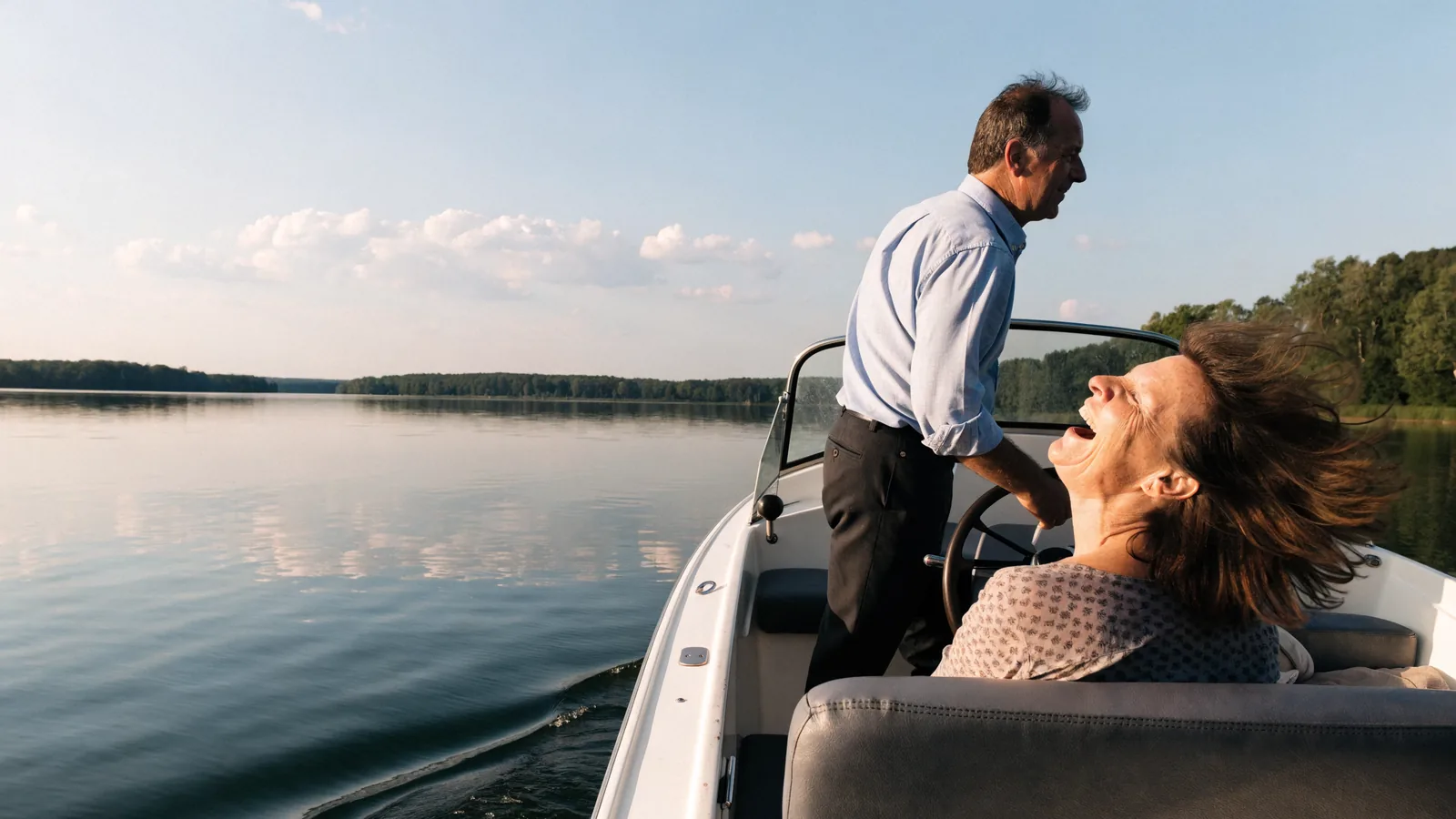Una pareja en su propia lancha: él lleva el timón, ella ríe con el pelo al viento, un lago con luz de verano