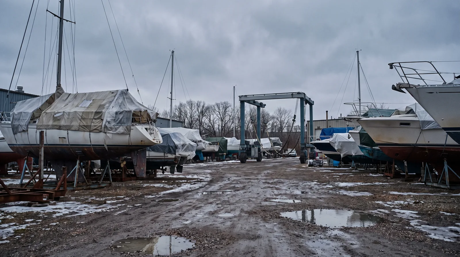 Barcos en seco para el invierno sobre cunas y cubiertos con lonas, con una grúa pórtico detrás