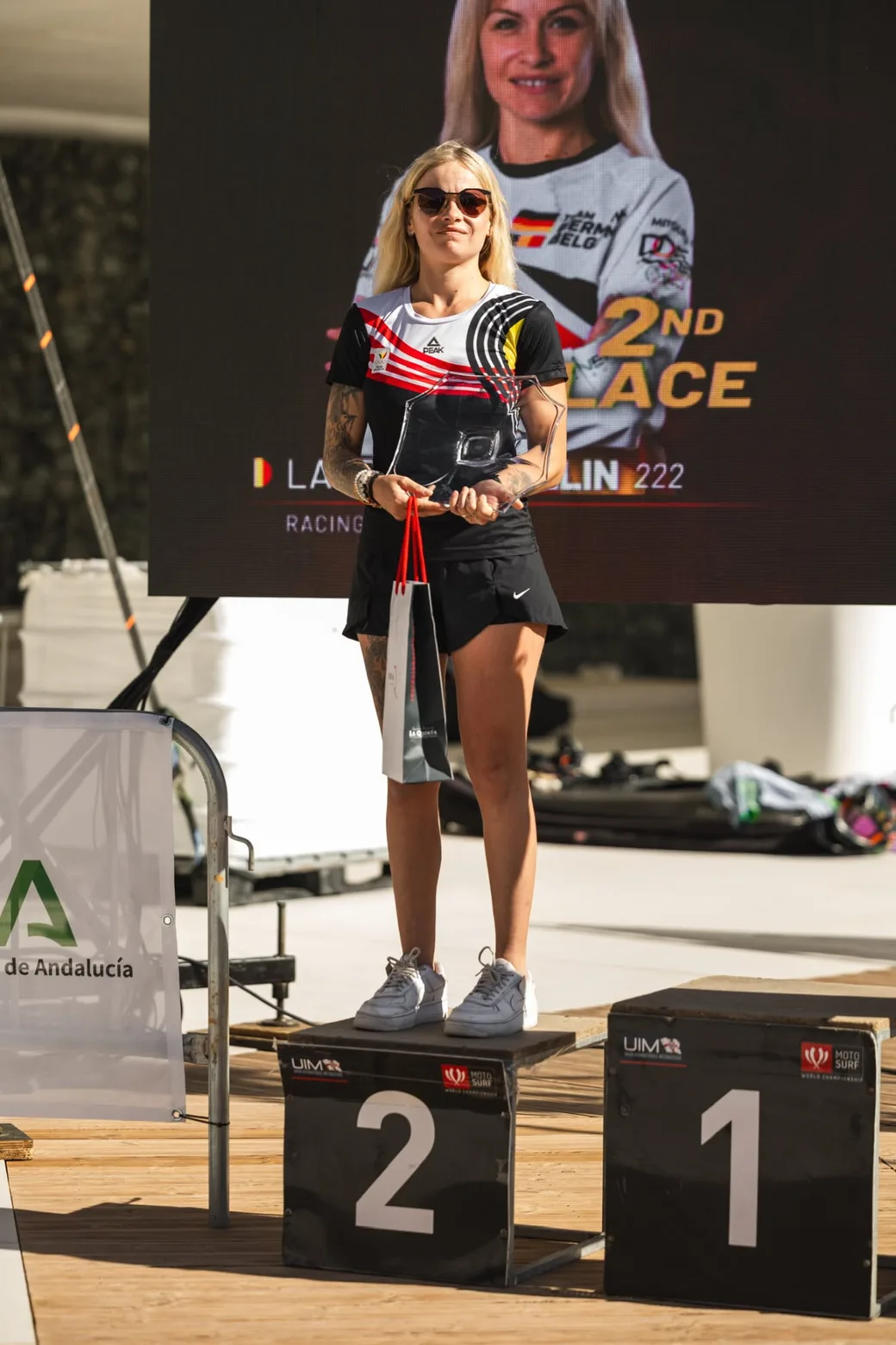 Laureen Thellin Deprez en el podio con su trofeo, la pantalla detrás anuncia el segundo puesto