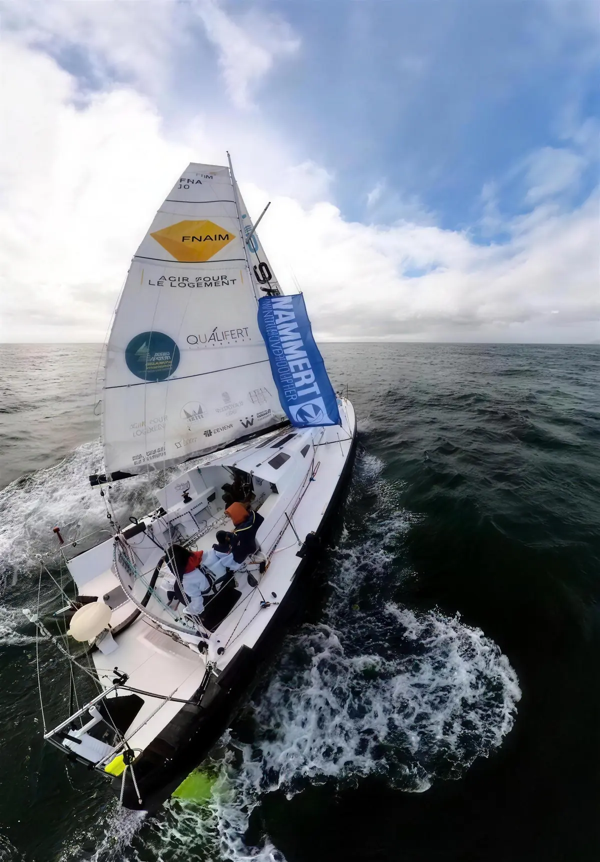 Velero navegando en mar abierto con una bandera de NAMMERT en la jarcia