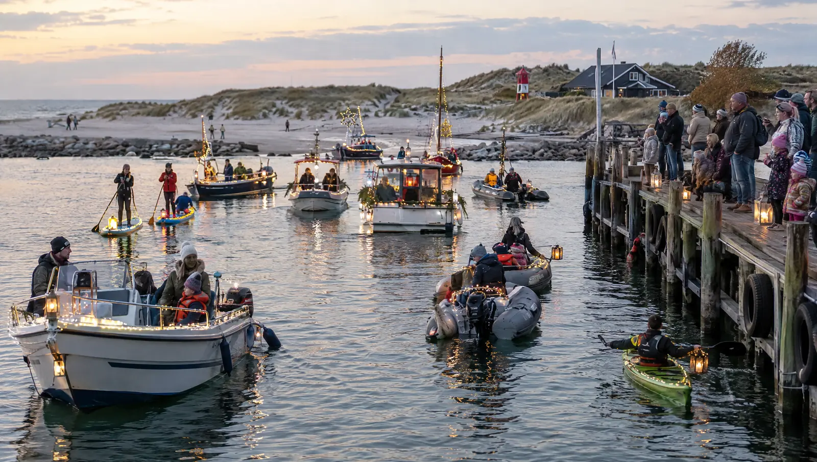 Barcos, kayaks y tablas de SUP decorados con luces en el puerto, público en el muelle