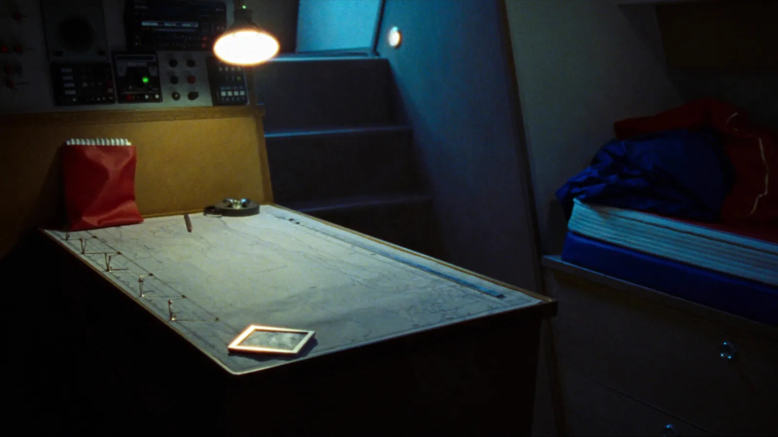 Mesa de cartas bajo cubierta con equipos de radio y lámpara de lectura