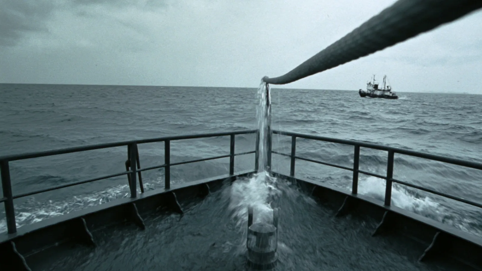 Cabo de remolque en tensión entre dos barcos sobre mar gris