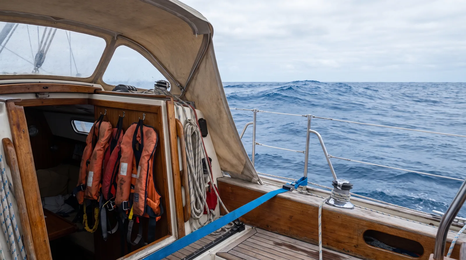 Chalecos salvavidas con arneses junto a la escalera de cámara de un velero de crucero en alta mar