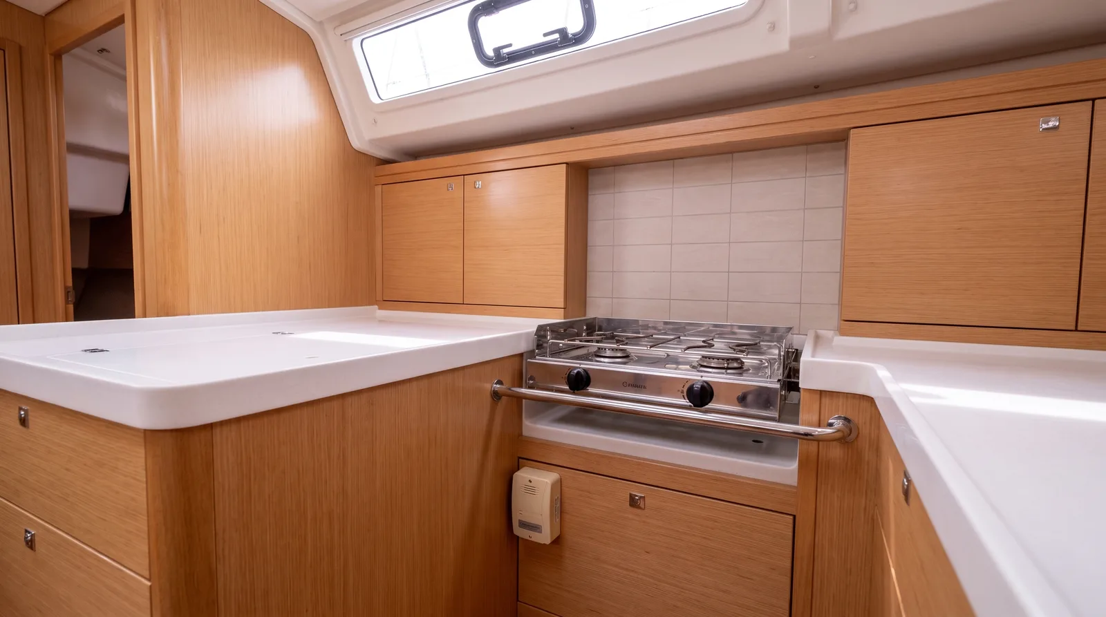 Cocina de gas con barandilla en la luminosa cocina de un velero, debajo un detector de gas cerca del suelo