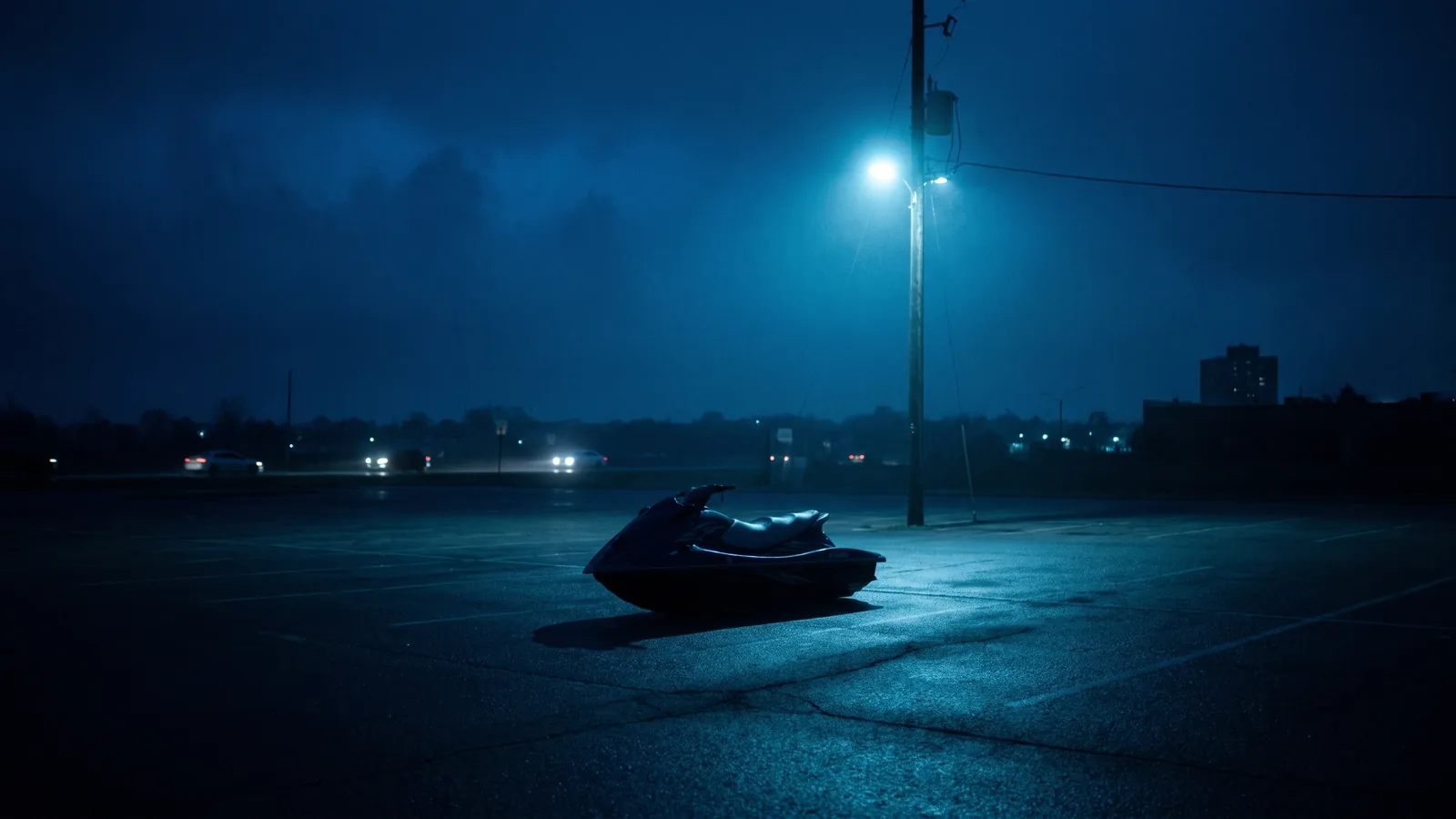 Una moto de agua sola de noche en un aparcamiento abierto bajo una farola