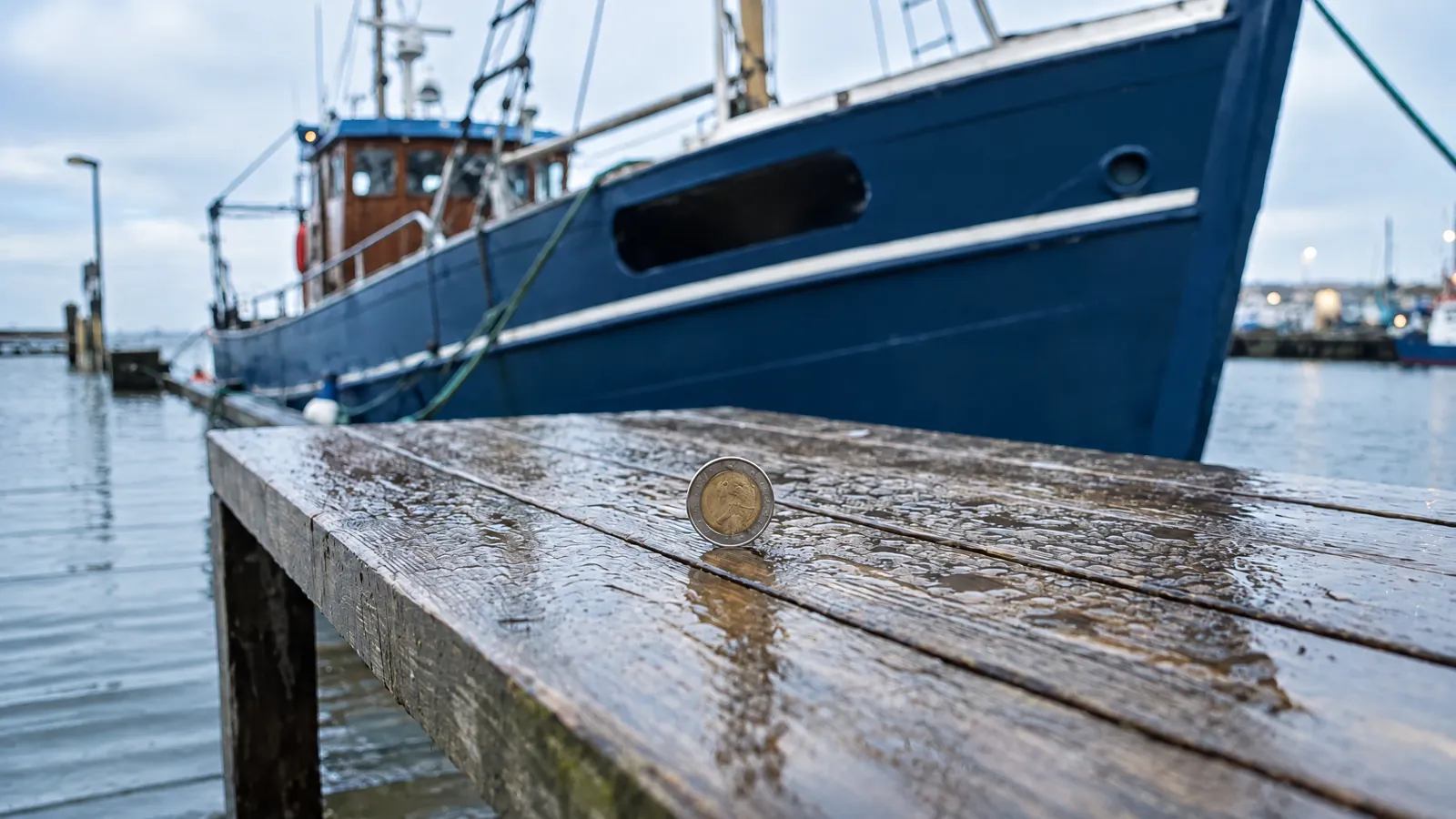 Una moneda de canto sobre la cubierta mojada de un barco amarrado