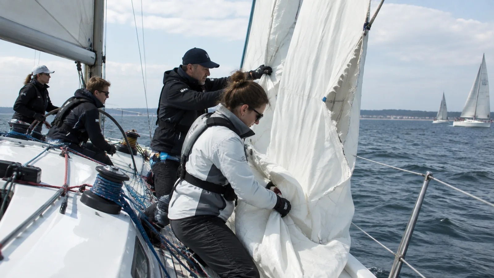 La tripulación de un barco de regatas trabaja en la proa con la vela izada