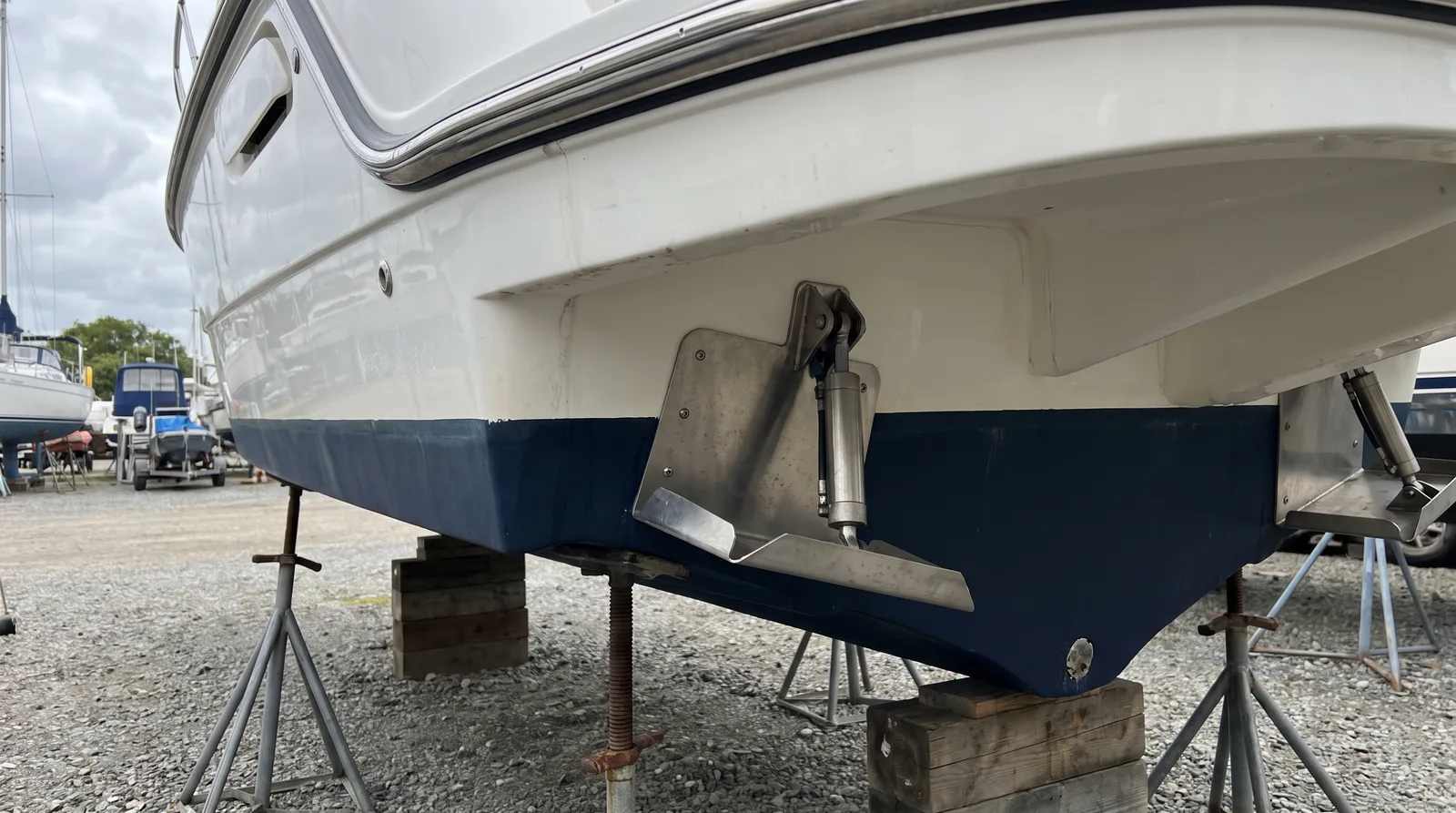 Espejo de popa de una lancha bien cuidada sobre una cuna con dos flaps de trim de acero inoxidable, uno doblado en el borde